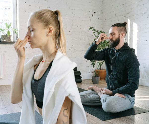 Man sitting in a calm cross-legged meditation pose indoors.